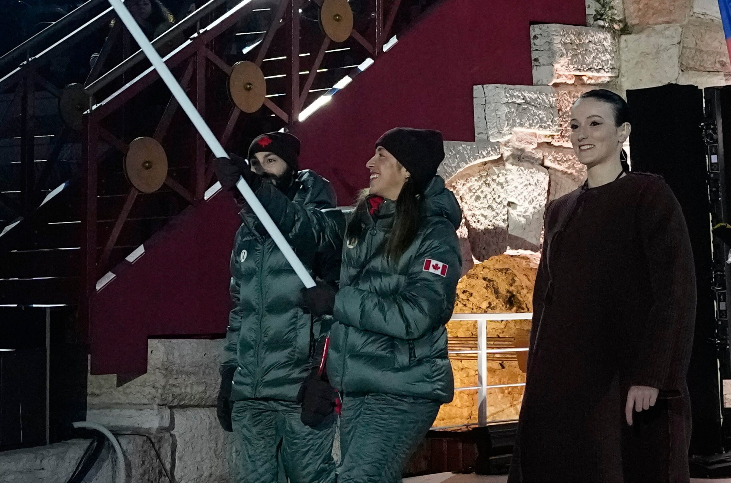 Valérie Maltais et Steven Dubois, du Canada, portent le drapeau de leur pays lors de la cérémonie de clôture des Jeux olympiques d’hiver de 2026, à Vérone, en Italie, le dimanche 22 février 2026. (Photo AP/Natacha Pisarenko).